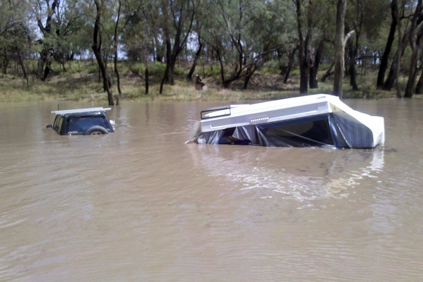 Floodwaters cover a car and caravan camped on the Condamine River.