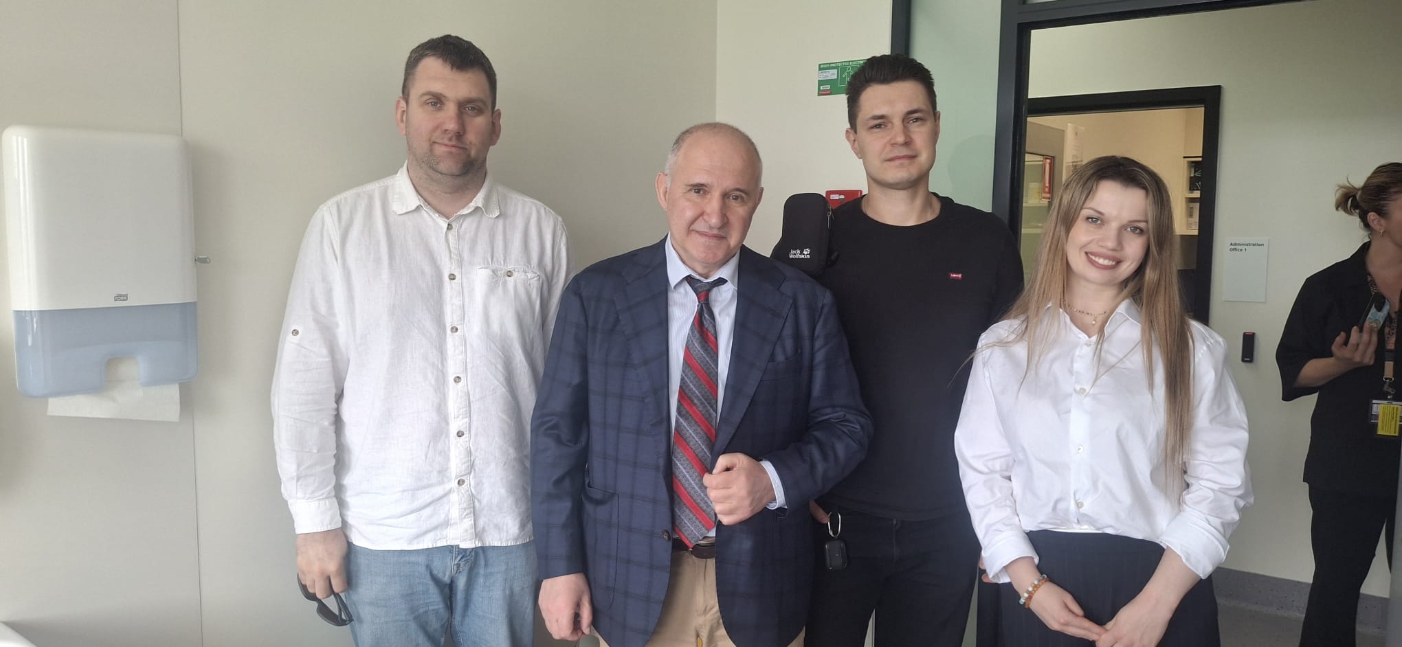 Cuatro médicos vestidos de civil, dos hombres más jóvenes, así como un hombre mayor y una mujer joven, posan para la cámara en una habitación de hospital. 