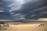 Storm clouds loom over beach.
