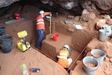 people in a cave measuring and digging