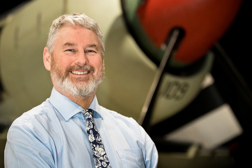 Nick Fletcher stands in front of a plane at the Australian War Memorial