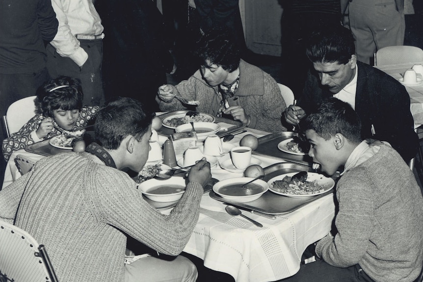 Black and white photo of family of five eating food