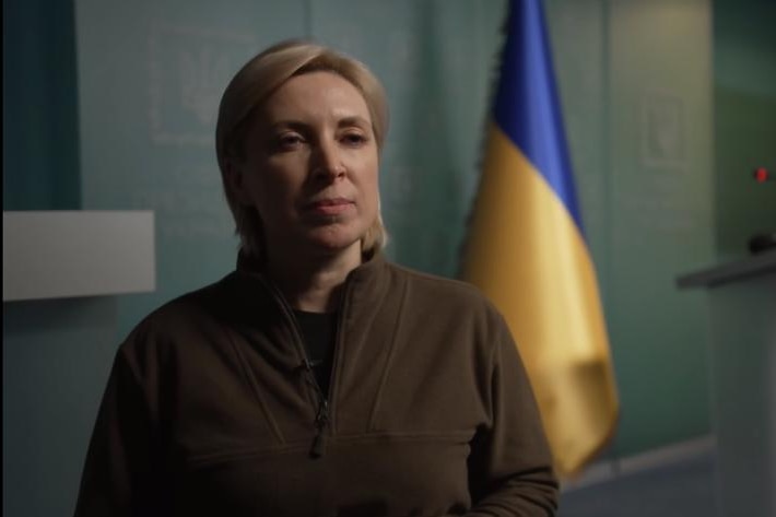 Close up of woman with Ukraine flag in background.
