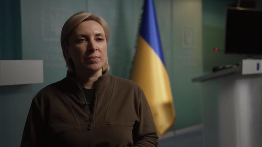 Close up of woman with Ukraine flag in background.