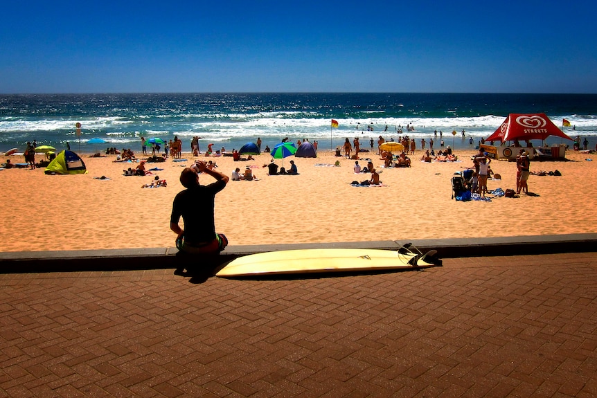 A surfer drinks water on a hot day in Sydney, 2013