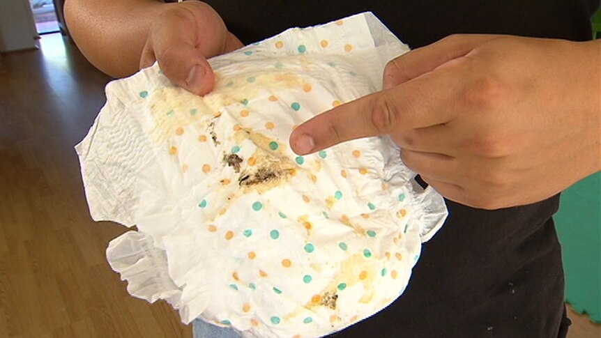 A man points to a nappy with some spider remains smeared on it.