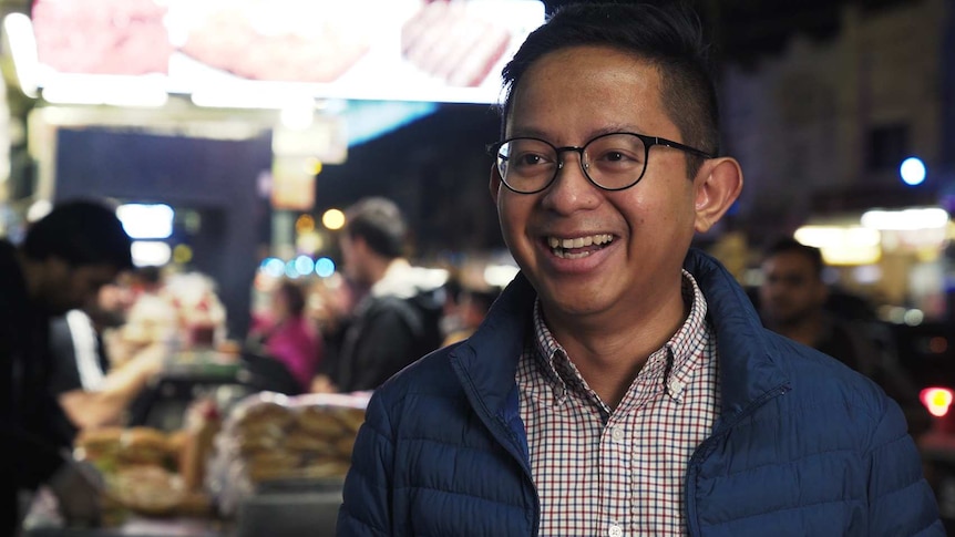 Ashraf Alias smiling at a bustling Ramadan night market for a story on foods eaten by Muslim Australians at Ramadan.