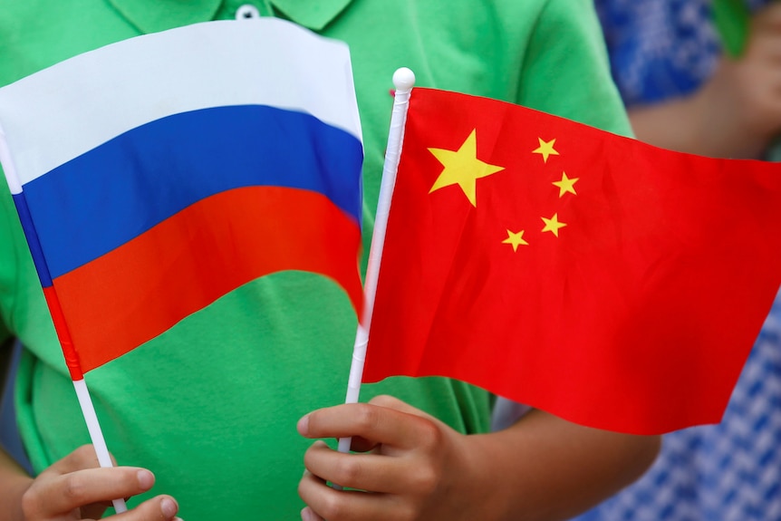 A child holds the national flags of Russia and China.