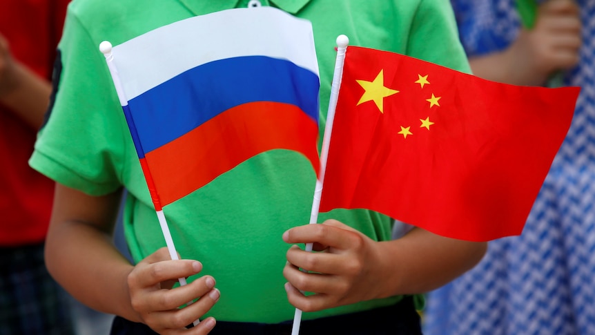 A child in green shirt told two small Chinese and Russian flags