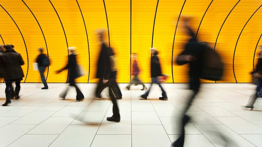 Blurred figures walk through a commuter tunnel