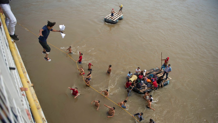 Migrants jump from a border bridge into the Suchiate River.
