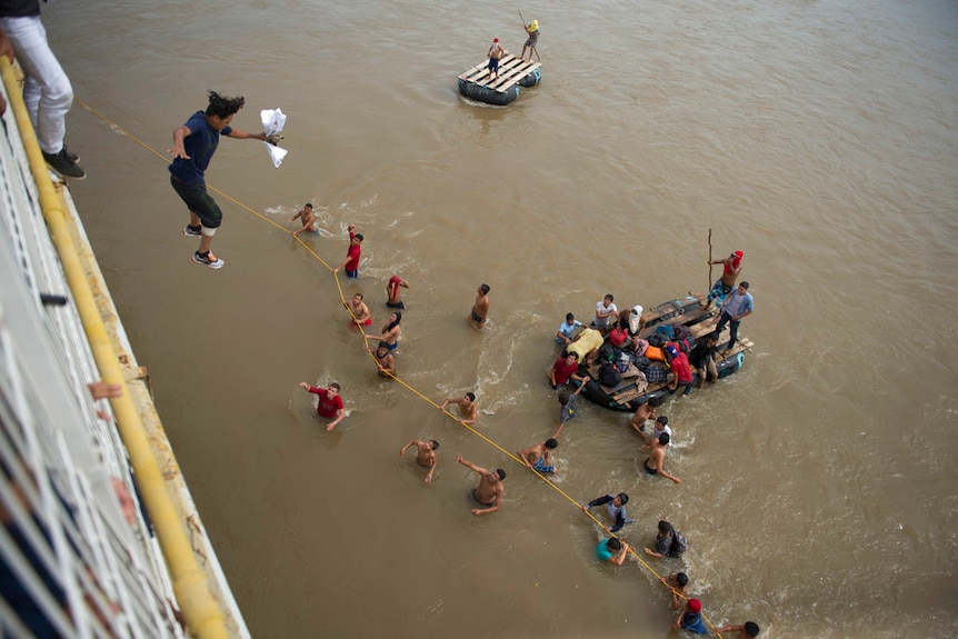 Migrants jump from a border bridge into the Suchiate River.