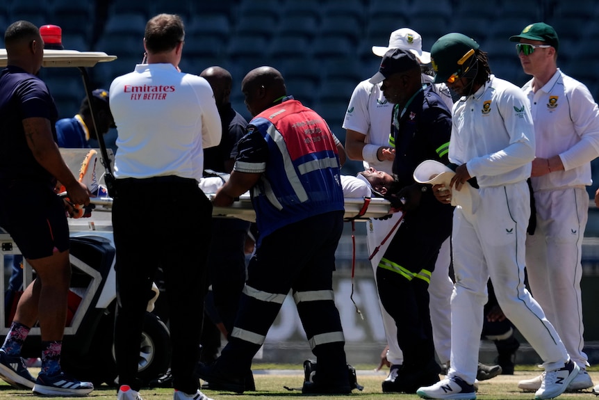 Keshav Maharaj is carried off the pitch on a stretcher as medical officials attend to him and teammates stand nearby
