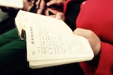 Woman holds a bible in a small underground church in Beijing