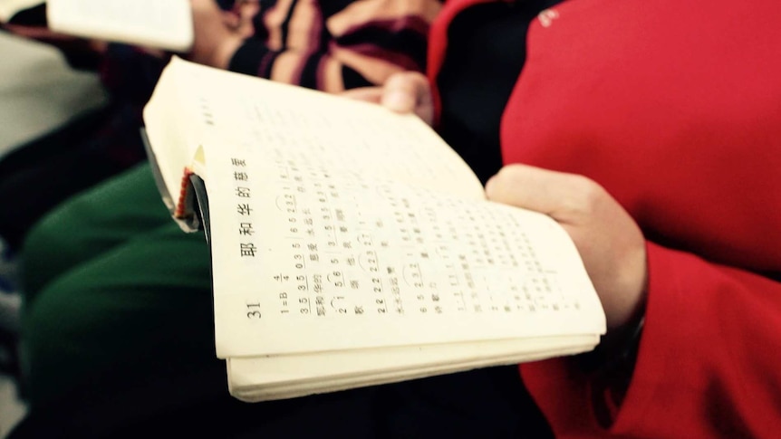 Woman holds a bible in a small underground church in Beijing