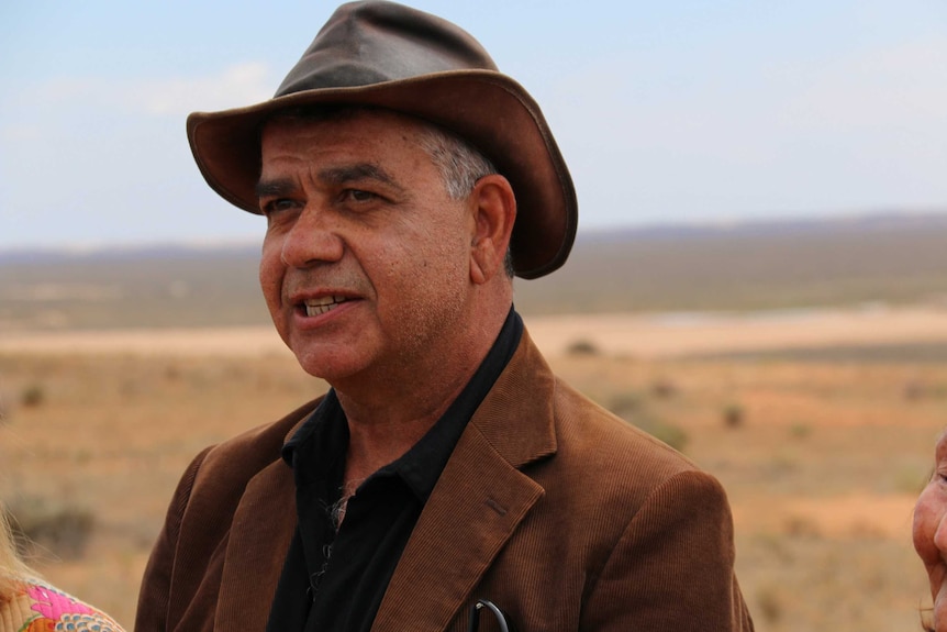 An Indigenous man in a jacket and Akubra-style hat.