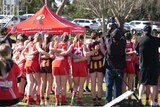 a group of female afl players form a circle