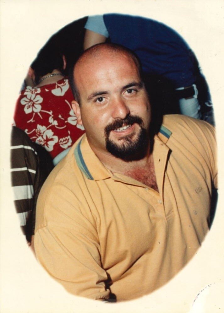 A man in a yellow polo shirt and a beard 