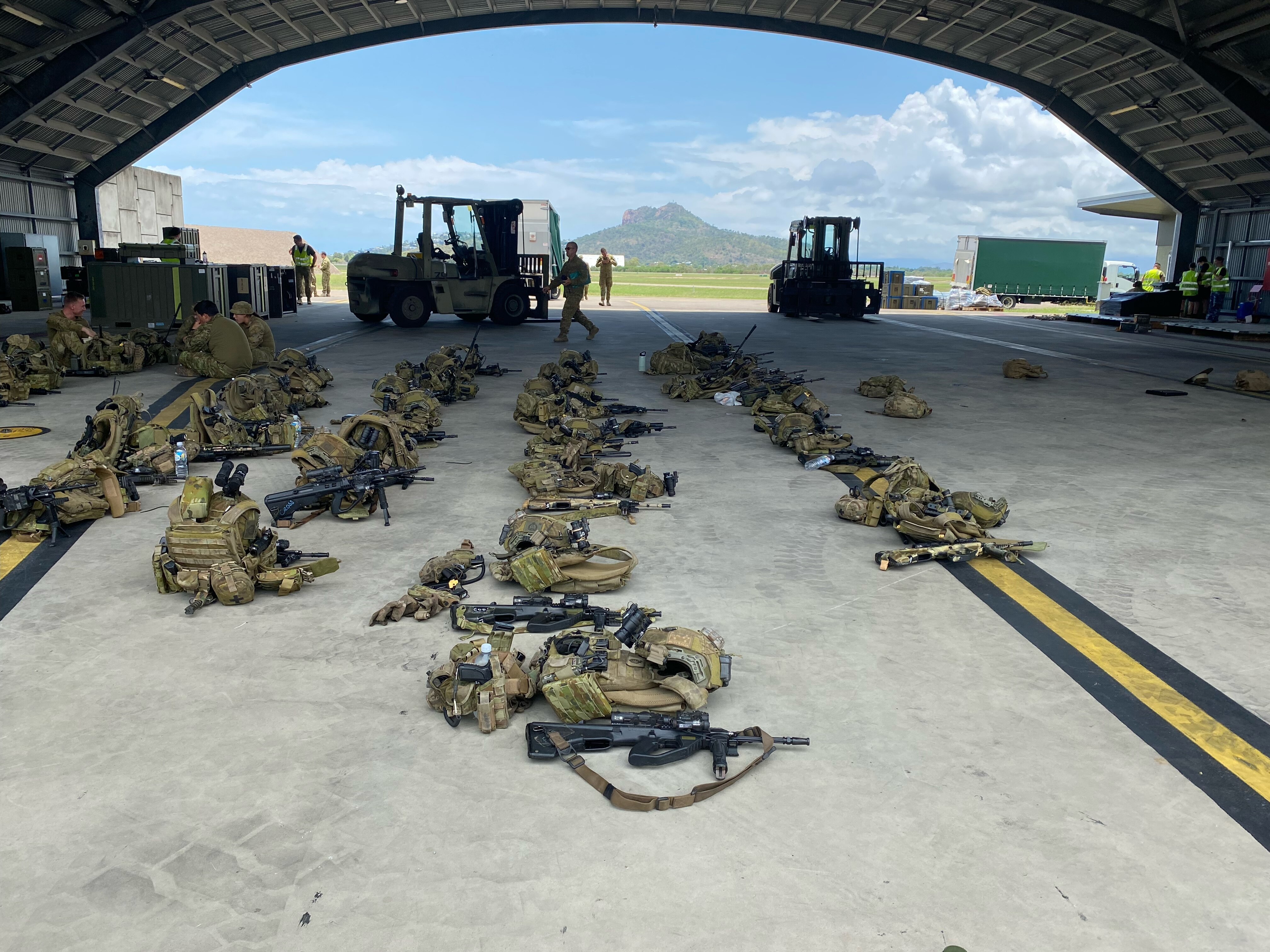 A picture of guns and army bags on the ground.