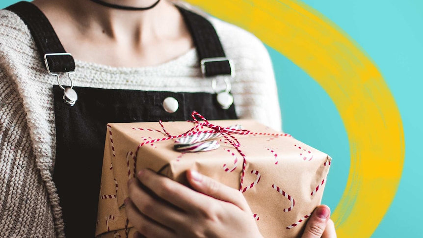Close-up of a woman holding a Christmas gift wrapped in brown paper in a story about Christmas gifts on a budget.