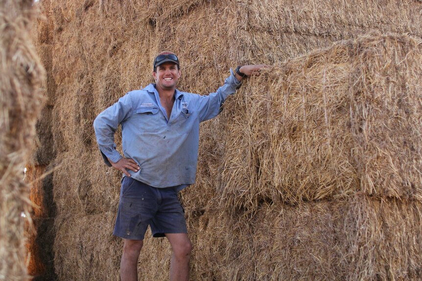 a man standing next to hay bales