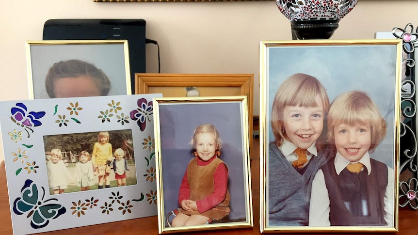 A collection of family pictures on a sideboard.