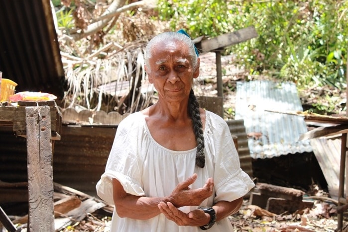 A woman stands in front of the damage caused by Typhoon Maysak