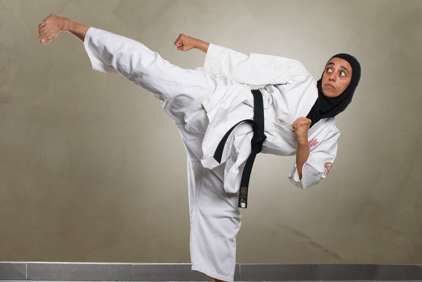 Sara Mokhtar performs a high kick wearing her black belt uniform.
