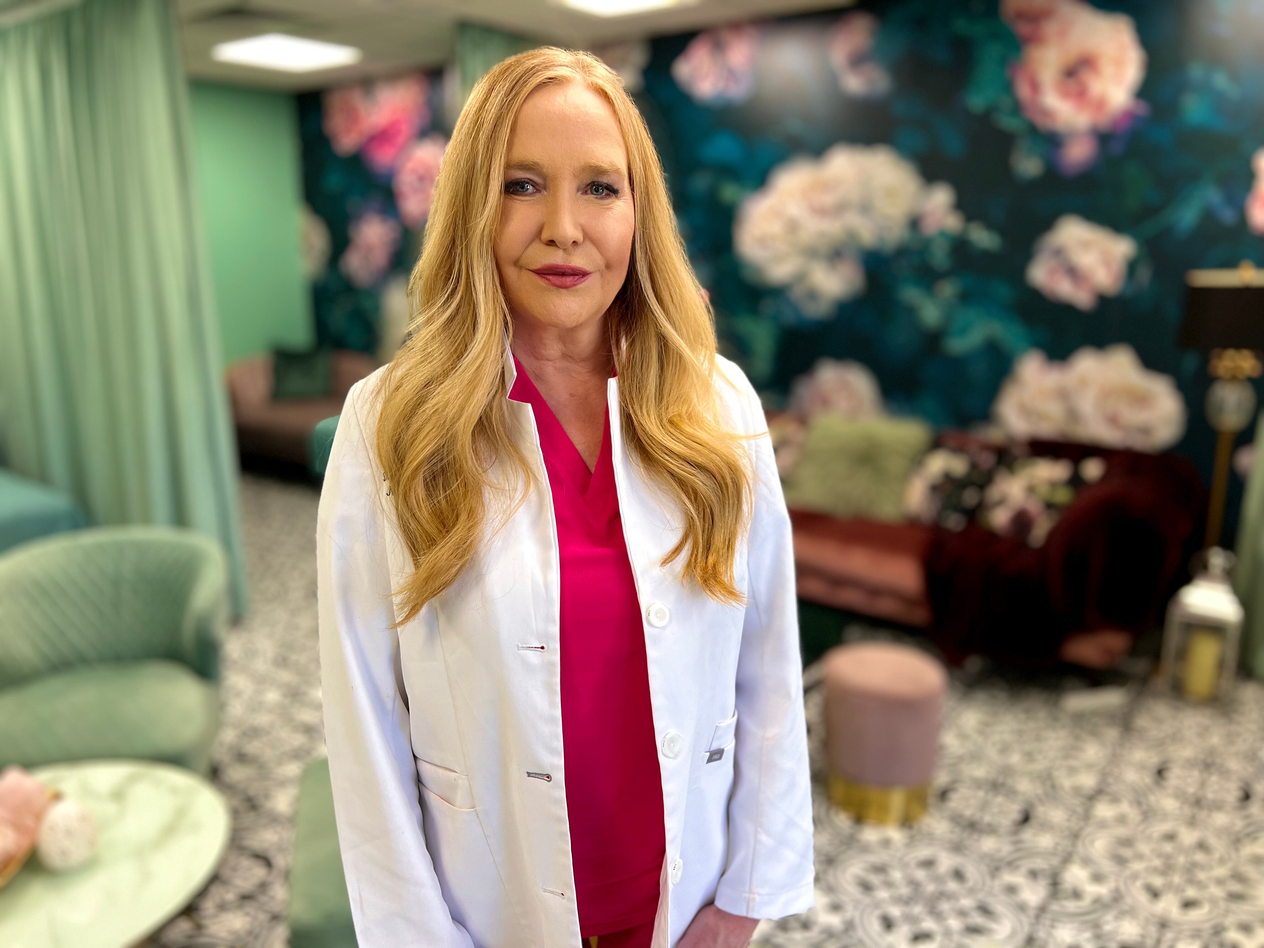 Woman doctor smiling at camera with floral wall paper and mint office decor in the background