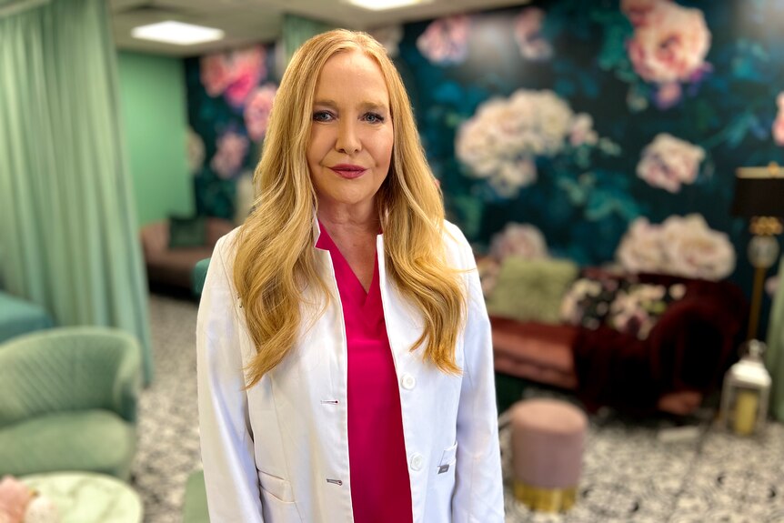 Woman doctor smiling at camera with floral wall paper and mint office decor in the background