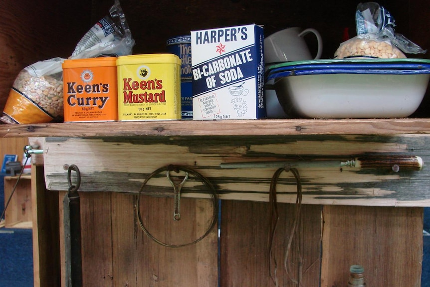 Old tins of Keen's Curry Powder, Keen's Mustard and bi-carb soda on a self in an old hut