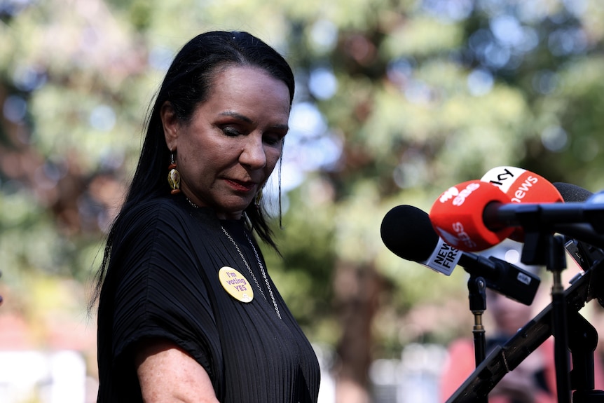 Linda Burney with her head down wearing a Yes badge. 