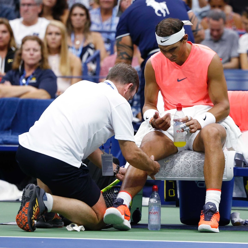 A male tennis player gets treatment on his knee