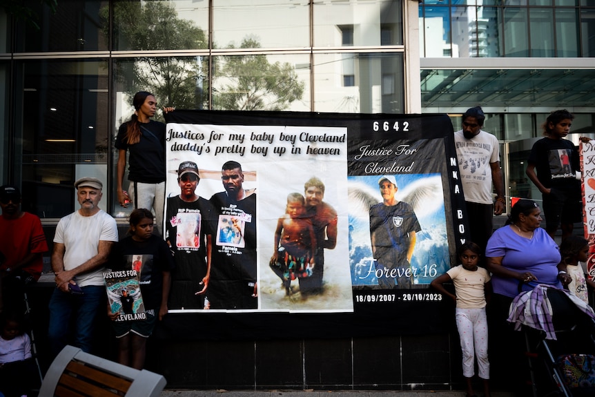 Family members of Cleveland Dodd hold large posters of Cleveland with messages calling for justice.
