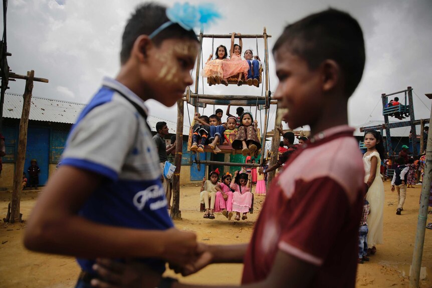 Children shaking hands and many others behind them in a makeshift ferris wheel