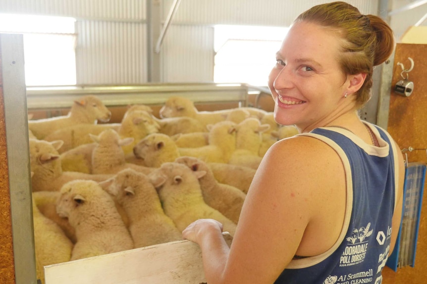 Allison Preston stands in front of a sheep pen.