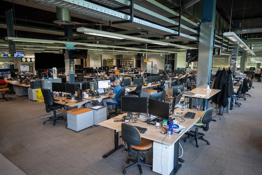 Two people sit inside a news room