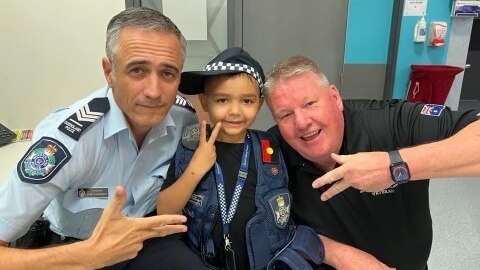 A small boy dressed as a police officer with two police officers.
