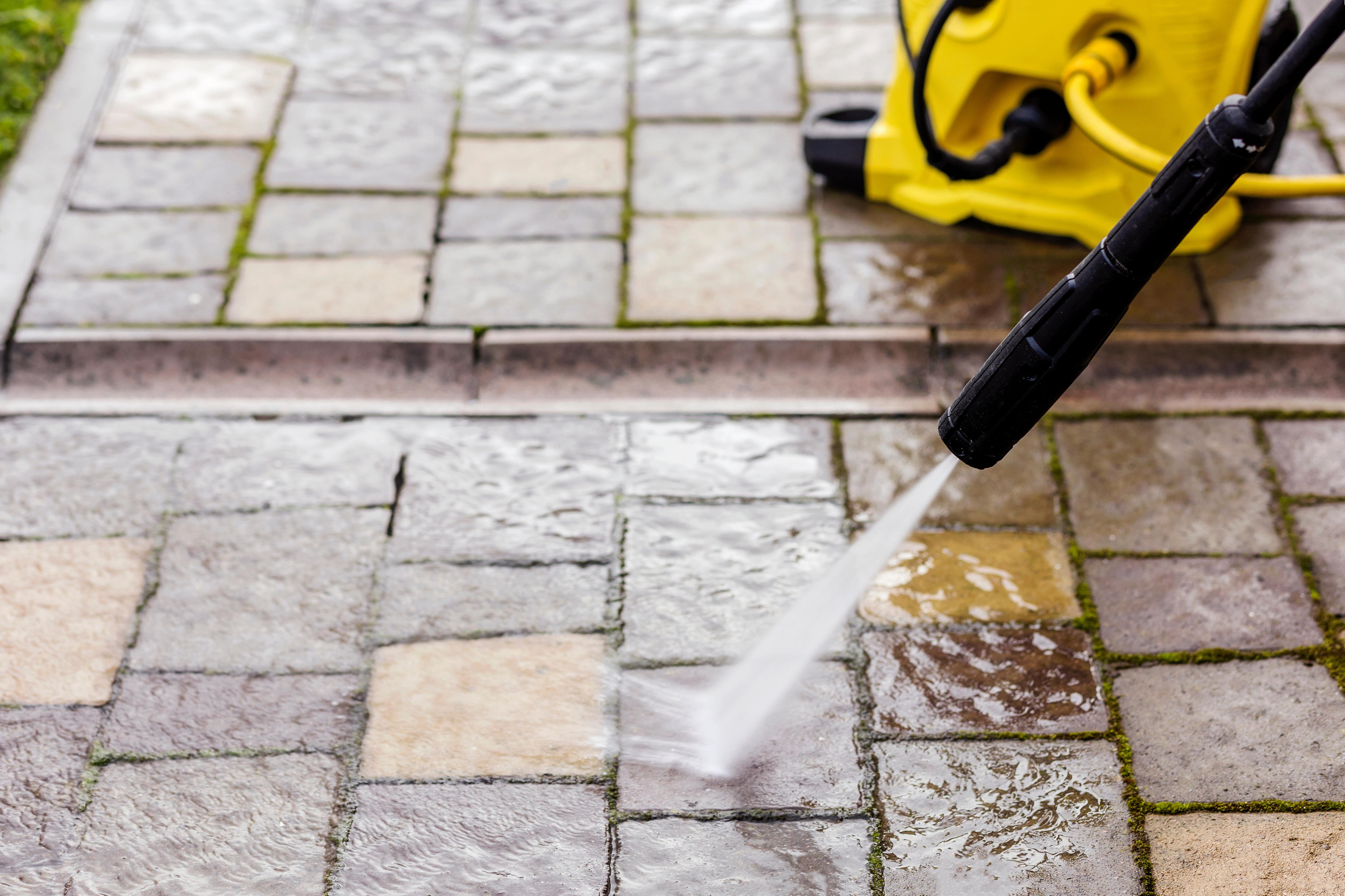 Clean paving stones in the garden with a high-pressure cleaner.