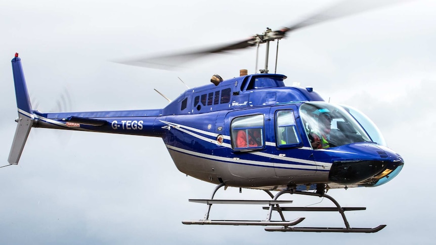 A blue helicopter flies in the air.
