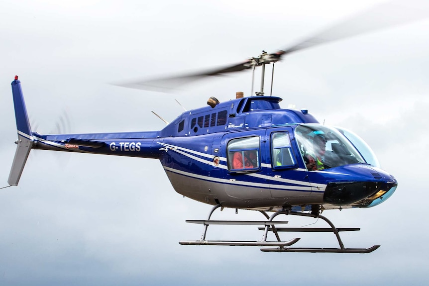 A blue helicopter flies in the air.