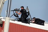 POlice officers on a roof look through the sights of their rifles. 