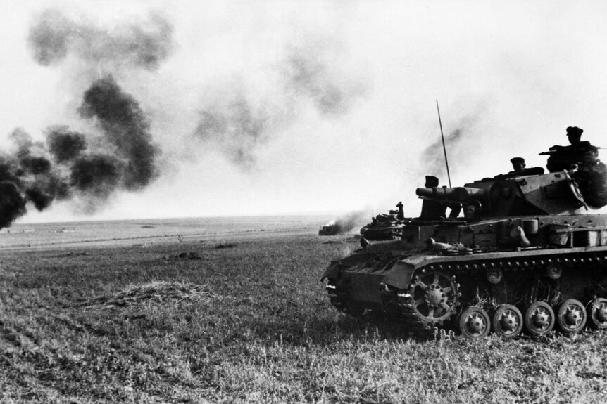 A German tank in the foreground of an open field. Another tank burning in the distance.