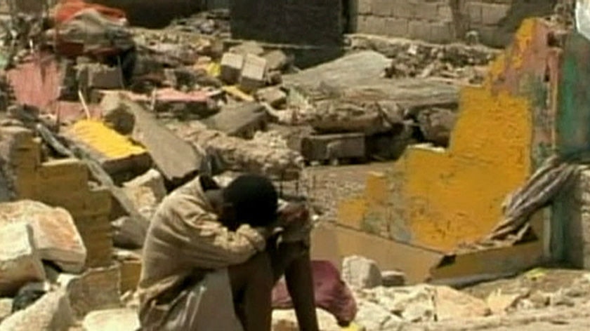 Still of boy with head in hands sitting in rubble in Gonaives, Haiti, following Hurricane Ike.