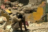 Still of boy with head in hands sitting in rubble in Gonaives, Haiti, following Hurricane Ike.