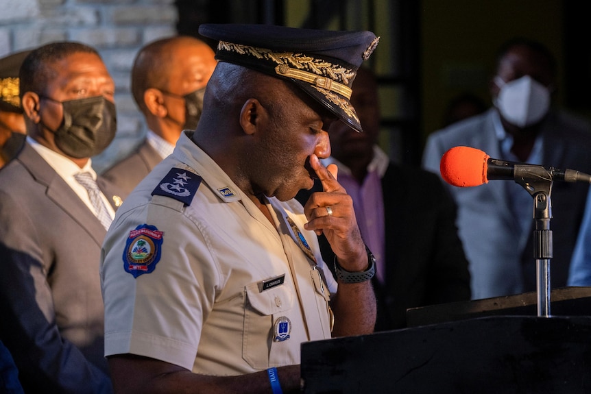 Leon Charles wearing a Haiti police uniform speaks behind a lectern. 