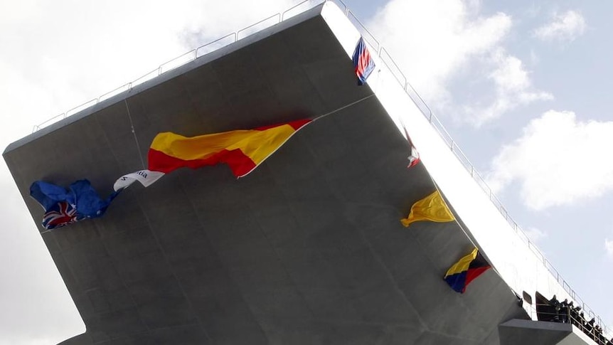 The hull of the first of the Royal Australian Navy's two new amphibious ships slips into the water