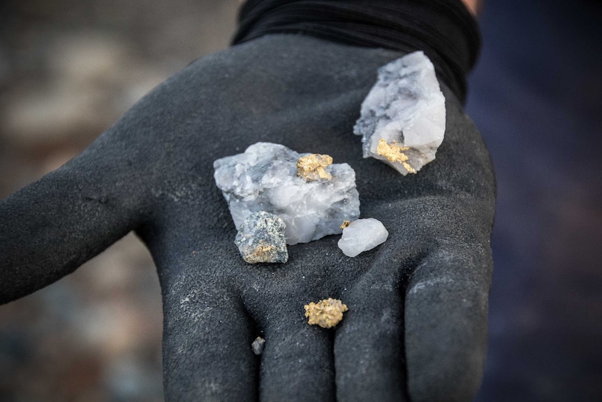 Gold specks being held by gloves.