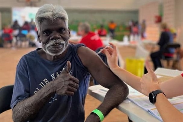 Maningrida traditional owner Reggie Wuridjal sits with his thumb up while getting vaccinated.