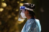 A woman dressed in PPE outside a quarantine hotel.